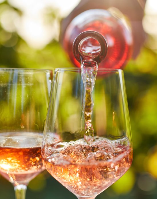 Pouring rose wine into glasses from a bottle